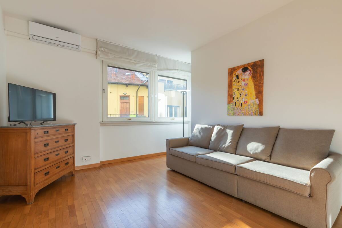 A living room with a wooden dresser, a beige sofa, and a painting on the wall.
