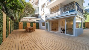 Un patio extérieur moderne doté d’une terrasse en bois, d’une table à manger avec des chaises et d’un espace salon abrité.