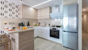 Una cocina moderna con una isla central, electrodomésticos de acero inoxidable y armarios de madera clara.