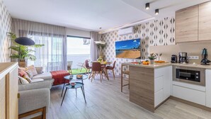Una sala de estar moderna con sofá, mesa de comedor y zona de cocina con horno empotrado.