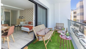 Un apartamento moderno con balcón, amoblado con sofá, sillas y una mesa de comedor.