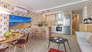 Una cocina moderna con una isla central, una zona de comedor con una mesa redonda y sillas, y un espacio de estar con un sofá y una mesita de centro.