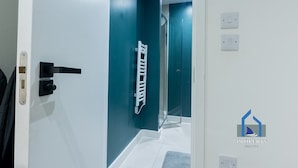Un intérieur moderne avec une porte blanche, une douche en verre et un mur d’accent de couleur turquoise.