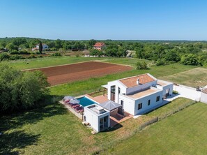 A modern house with a swimming pool, surrounded by fields and trees. - Brand new modern Villa with pool ,completely fenced. (Unknown)
