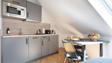 A modern kitchen with grey cabinets, a microwave, and a dining area with a table and chairs.