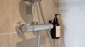 A shower with a chrome hose and wall-mounted controls.