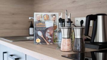 A kitchen counter with a cookbook, salt and pepper shakers, a coffee maker, and a kettle.