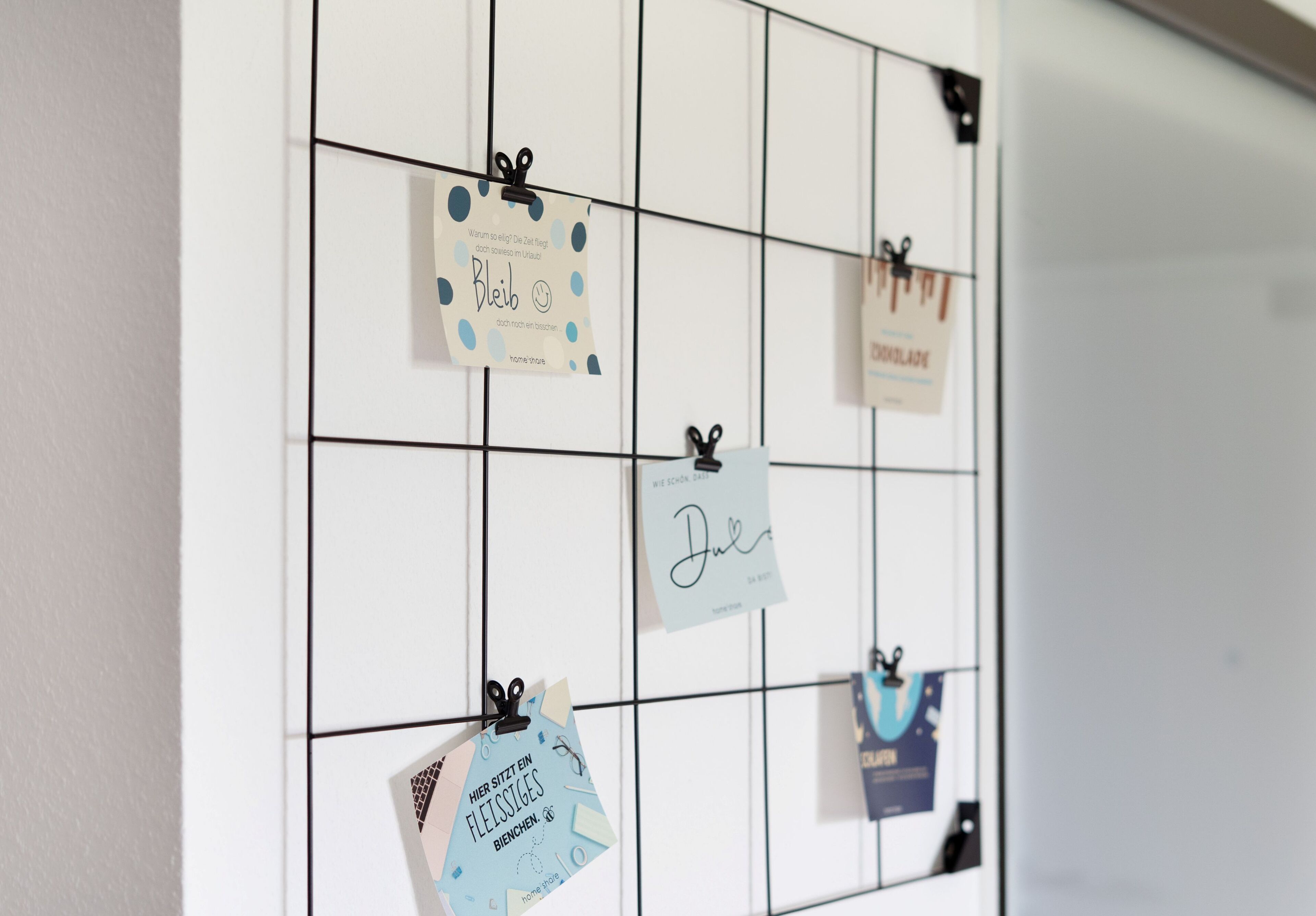 A wall with a grid of square sections, each holding a card with text and a clip.