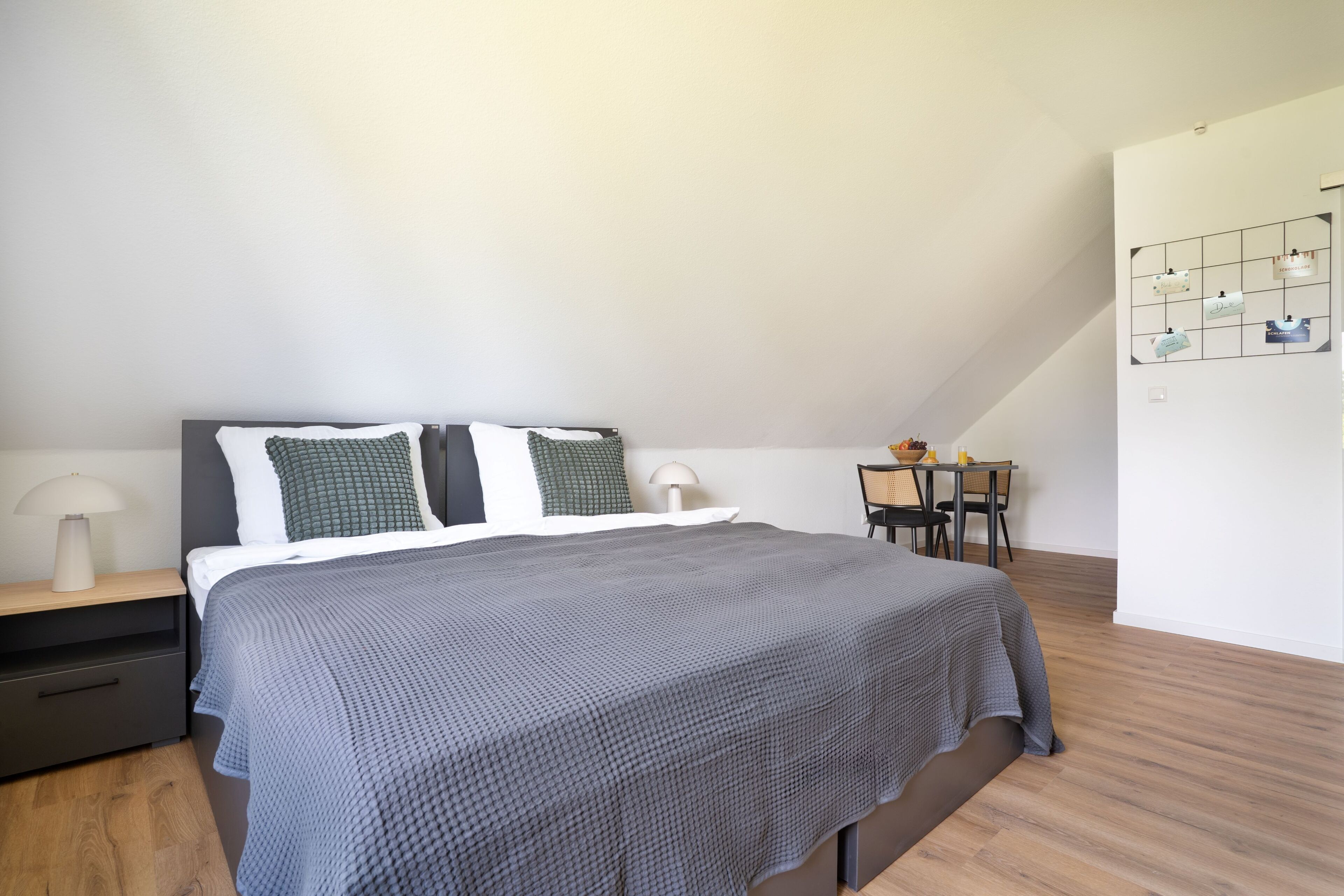 A modern bedroom with a bed, nightstand, and a small desk with a chair.