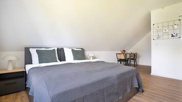 A modern bedroom with a bed, nightstand, and a small desk with a chair.
