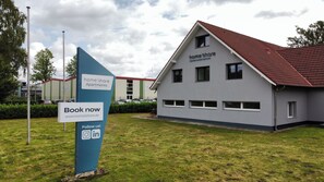 A modern building with a sign advertising 'home2share apartments' and a 'Book now' prompt. - Schöne Apartments in Lohne I home2share (Lohne)