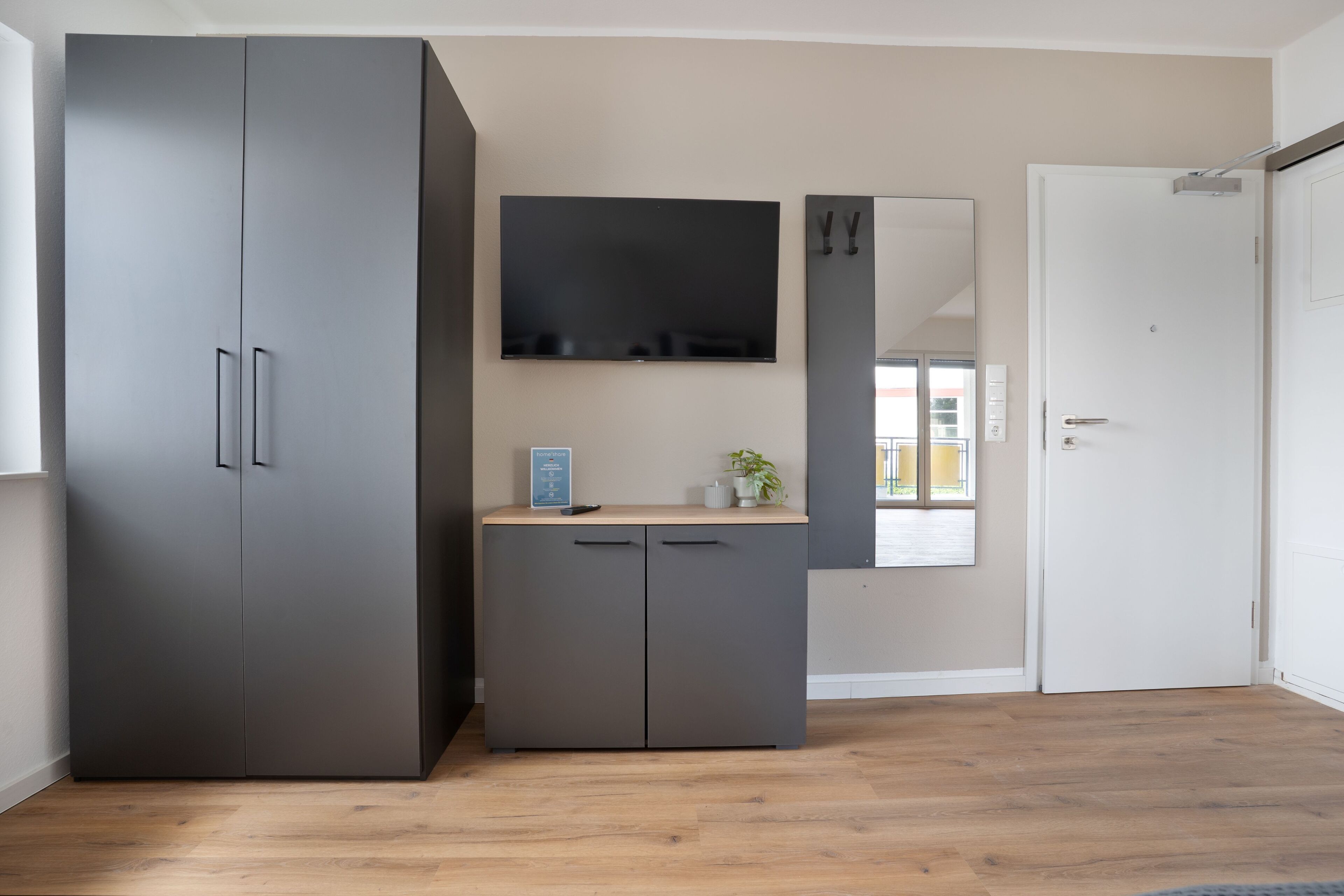 Ein Zimmer mit großem Kleiderschrank, einem flachbildfernseher an der Wand und einer Tür.