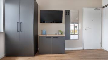 Ein Zimmer mit großem Kleiderschrank, einem flachbildfernseher an der Wand und einer Tür.