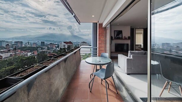 A balcony with a city view, a glass door, and a seating area with a table and chairs. - EP| Modern 2BR W/Workspace, Fast Internet, SmartTv (Medellín)
