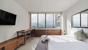 A modern hotel room with a large bed, a desk, and a TV mounted on the wall. - EP| Modern 2BR W/Workspace, Fast Internet, SmartTv (Medellín)