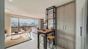 A modern apartment with a dining area, a large window with a city view, and a wardrobe. - EP| Modern 2BR W/Workspace, Fast Internet, SmartTv (Medellín)