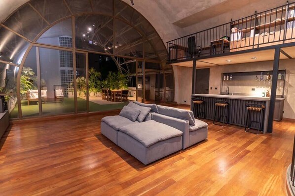 A spacious living area with a large glass wall, a modern kitchen, and a balcony.