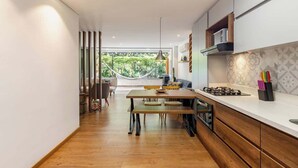 A modern kitchen with wooden cabinets, a white countertop, and a view of greenery outside. - |EP| Bright Apt w/Terrace, AC, BBQ and Workspace (Medellín)