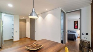 A modern interior with a wooden dining table, a pendant light, and a yellow chair. - |EP| Bright Apt w/Terrace, AC, BBQ and Workspace (Medellín)