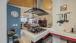A modern kitchen with a central island, a built-in stove, and a stainless steel range hood. - EP|  3 bed/ Br Apt W/city views, Great Location (Medellín)