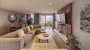 A modern living room with a sofa, a coffee table, and a TV mounted on the wall.
