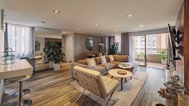 A modern living room with a sofa, coffee table, and dining area.