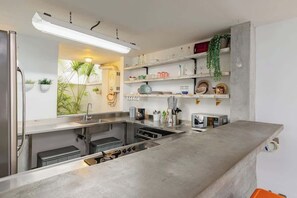 A modern kitchen with stainless steel appliances, white cabinetry, and a concrete countertop.