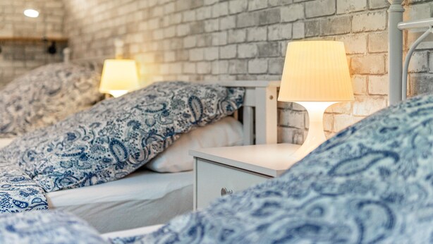 A bedroom with a brick wall, two bedside tables with lamps, and patterned bedding.