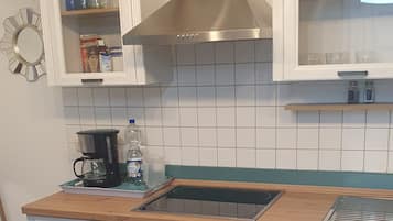 Une cuisine compacte équipée d’une cuisinière, d’un four et d’une machine à café posée sur le plan de travail.