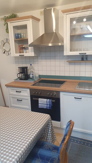 Eine kleine Küche mit einem Herd, Backofen und einer Kaffeemaschine auf der Arbeitsfläche.