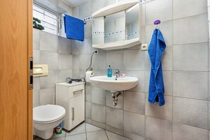 Ein Badezimmer mit Toilette, Waschbecken, Spiegel und Handtüchern.