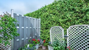 A garden with a wooden fence, potted plants, and a white lattice structure.