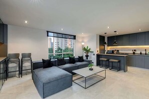 A modern apartment with a grey sofa, a glass coffee table, and a kitchen area with bar stools. - |EP| Spacious Apt with AC, Workspace, Views (Medellín)
