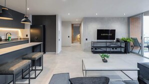 A modern kitchen with a built-in fridge, a dining area with a TV, and a seating area with a plant. - |EP| Spacious Apt with AC, Workspace, Views (Medellín)