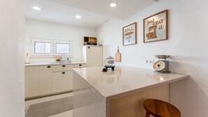 A modern kitchen with white cabinets, a marble countertop, and two wall-mounted signs. - Retiro T2 c/Piscina em Porches por Lovelystay (Alporchinhos)