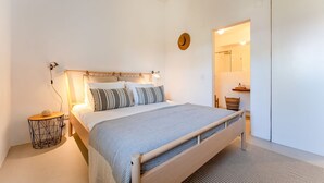 A bedroom with a wooden bed, a bedside table, a wall-mounted lamp, and a small round mirror. - Retiro T2 c/Piscina em Porches por Lovelystay (Alporchinhos)