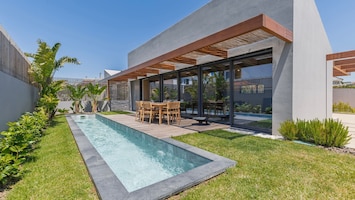 Outdoor deck beside a sleek pool, ideal for relaxing or dining al fresco in a private garden setting. #PT #Portugal #Ericeira #PoolsideVibes #OutdoorDining #TranquilGetaway