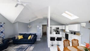 Eine moderne Wohnung mit Wohnzimmer, Küche, Essbereich und einer Treppe zu einer oberen Etage.
