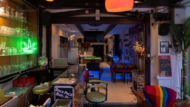 Un espace bar agrémenté d’un néon, d’une table de billard et d’une enseigne indiquant l’emplacement d’un bar à cocktails à emporter.