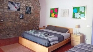 A bedroom with a stone wall, a bed with a wooden frame, a nightstand, and a lamp. - Suite in Tuscan farmhouse between Florence and Arezzo with wifi and pool (Pian di Scò)
