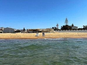 Une plage aux eaux cristallines, un rivage sablonneux et un bâtiment doté d’une zone abritée.