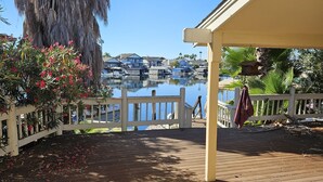 A wooden deck with a white railing, overlooking a marina with boats and houses in the background. - Waterfront Elegance (Discovery Bay)