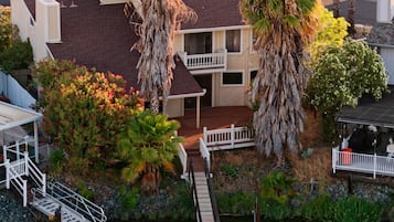 A residential area with a dock and boats, surrounded by palm trees and houses.