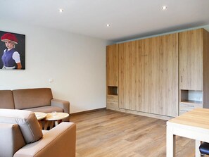A modern living room with a sofa, a round coffee table, and a wooden wardrobe.