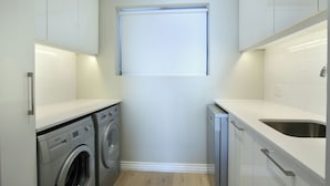 A compact kitchen with a washing machine, a sink, and a window.