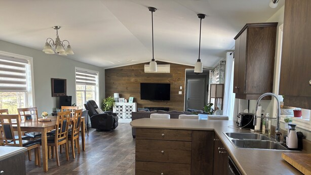 A modern kitchen with wooden cabinets, a built-in oven, and a large island with a sink. - Coastal Trail Getaway (Port Hood)