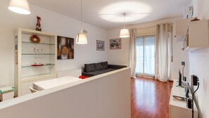 A modern living room with a sofa, a glass cabinet with decorative items, and a dining area with a white table and chairs. - Bacchilide Novanta by Wonderful Italy (Syracuse)