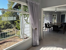 Un comedor moderno con una mesa grande y sillas, un ventilador de techo y vistas al exterior.