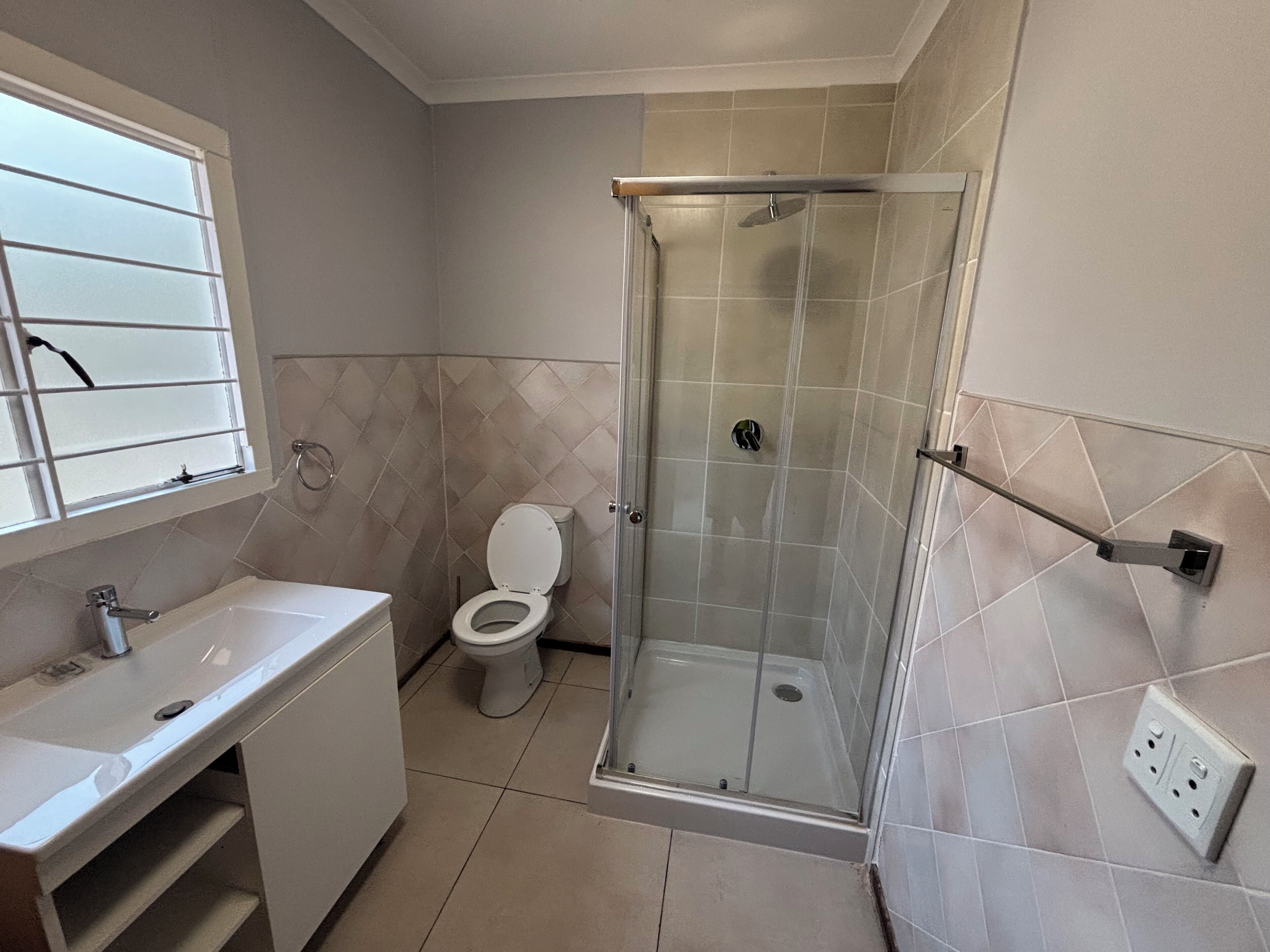 Un baño con ducha de mampara de vidrio, inodoro y lavabo.