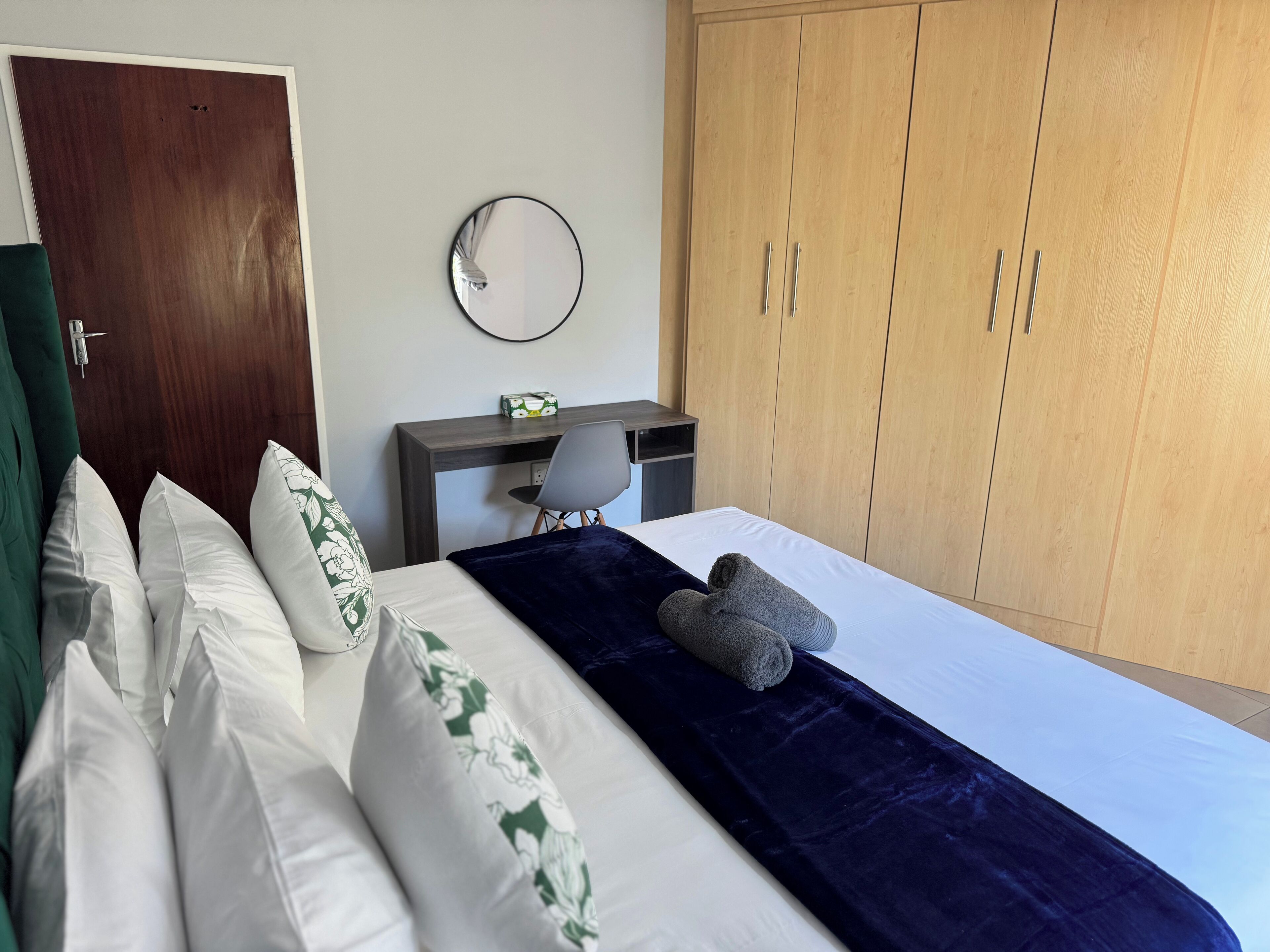A bedroom with a bed, a desk, a chair, and a wardrobe.